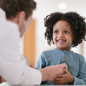 Child smiling with doctor checking her with stethoscope | BCBS of Tennessee