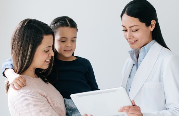 Female doctor showing mother and daughter information on a clipboard | BCBS of Tennessee