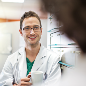 Male doctor in white coat holding coffee mug | BCBS of Tennessee