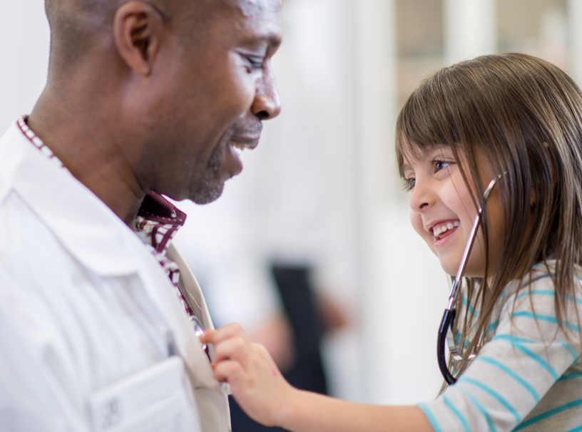 Child smiling while using stethoscope on doctor | BCBS of Tennessee