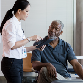 Younger female explaining information to an elderly man sitting on chair | BCBS of Tennessee