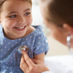 Young female child smiling while being examined with a stethoscope